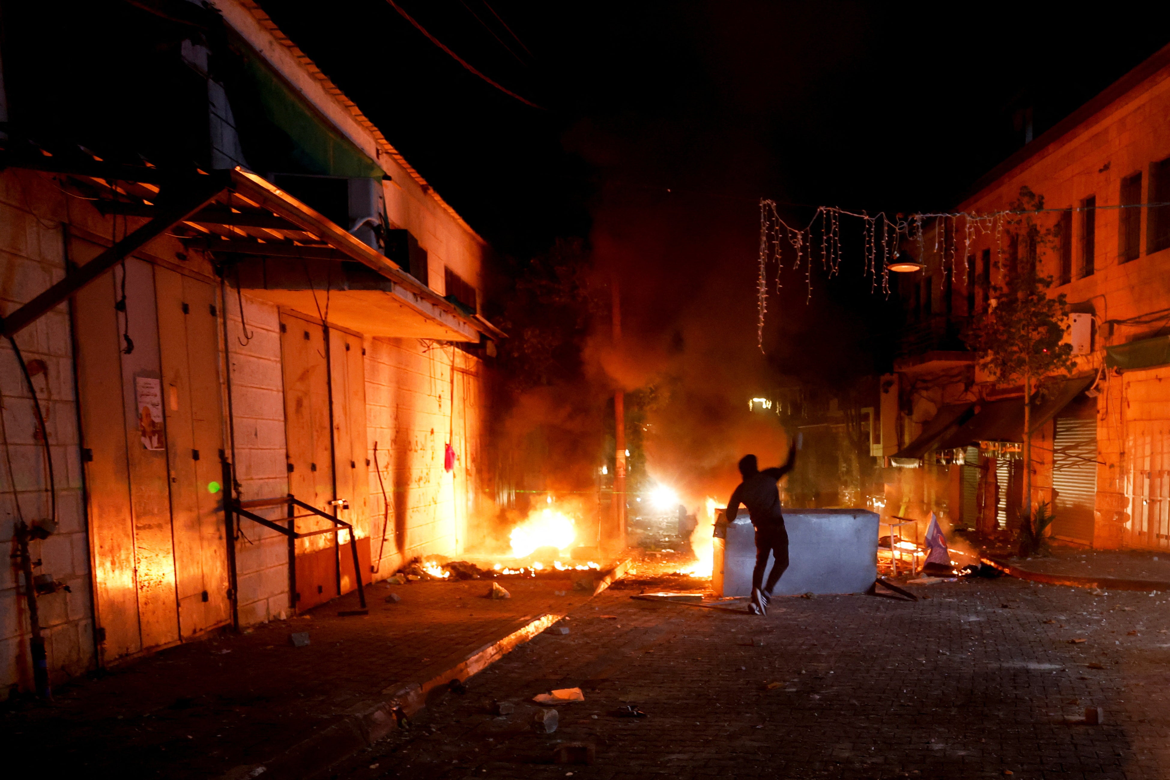 A Palestinian throws stones as the Israeli army raids Ramallah, in the Israeli-occupied West Bank