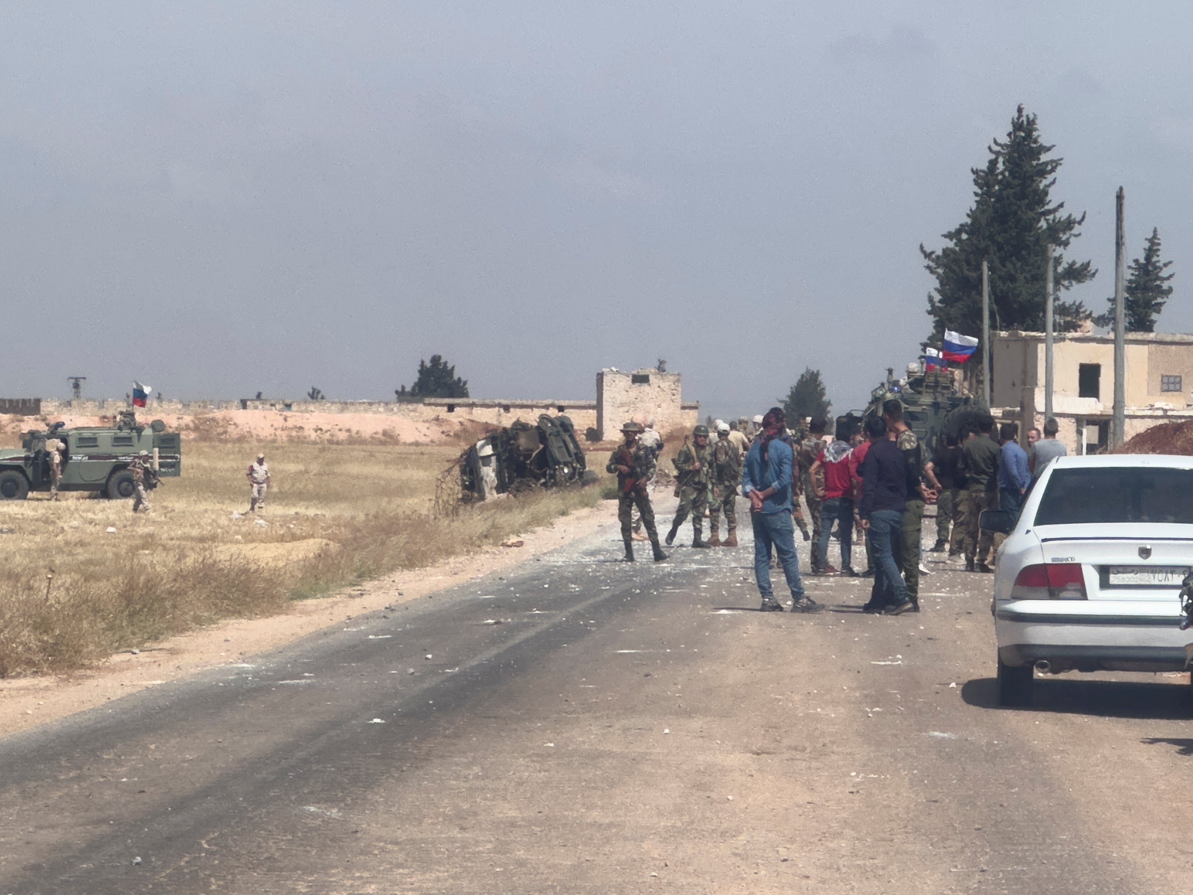 Russian military vehicles are parked near an overturned military vehicle, following an attack that the Syrian Observatory for Human Rights