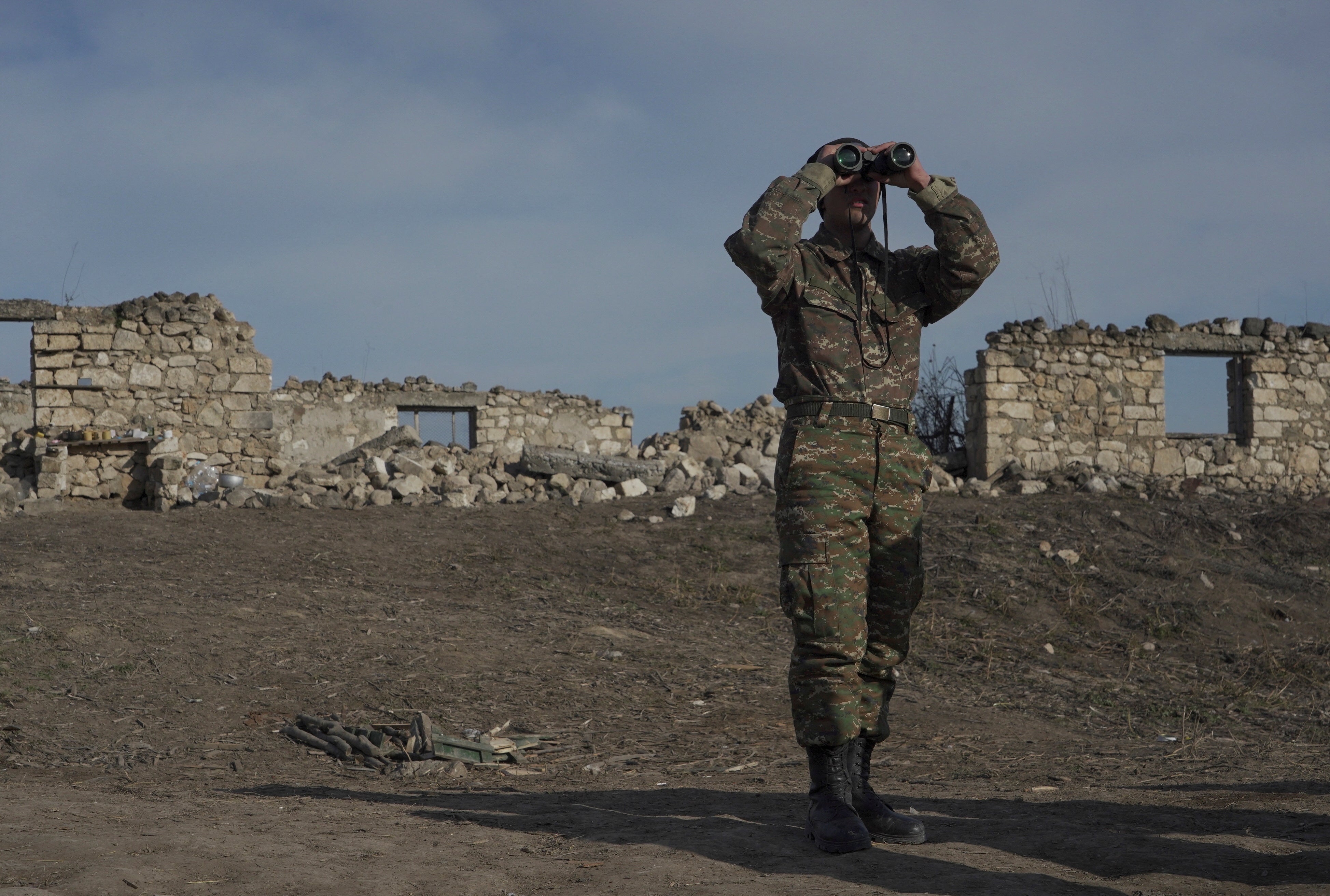 An ethnic Armenian soldier looks through binoculars as he stands at fighting positions near the village of Taghavard in the region of Nagorno-Karabakh
