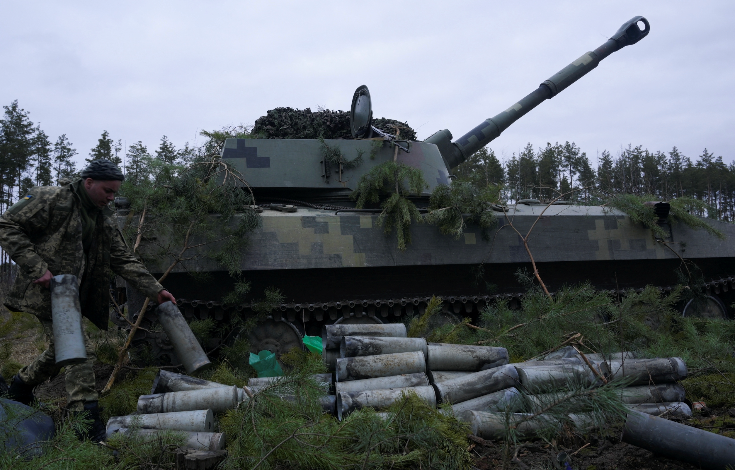 A service member of the Ukrainian armed forces carries an empty shell from a self-propelled howitzer