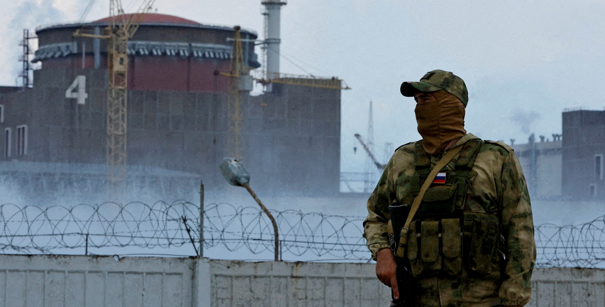 A serviceman with a Russian flag on his uniform stands guard near the Zaporizhzhia Nuclear Power Plant
