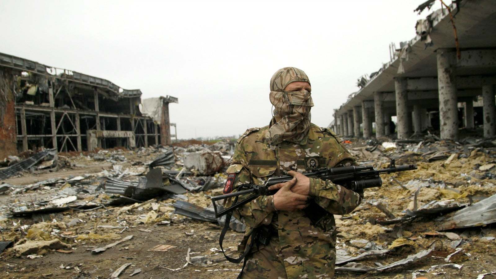 A member of the self-proclaimed Donetsk People's Republic forces stands guard near buildings destroyed during battles with Ukrainian