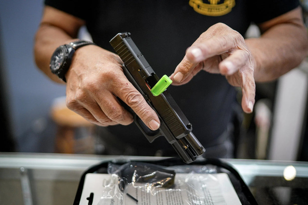 Arnie Gallegos, owner of ABQ Guns in Albuquerque, New Mexico, handles a handgun in an archival photograph. Gun rights organizations filed a new federal lawsuit on October 19, 2026, challenging the state's continued enforcement of its seven-day firearm
