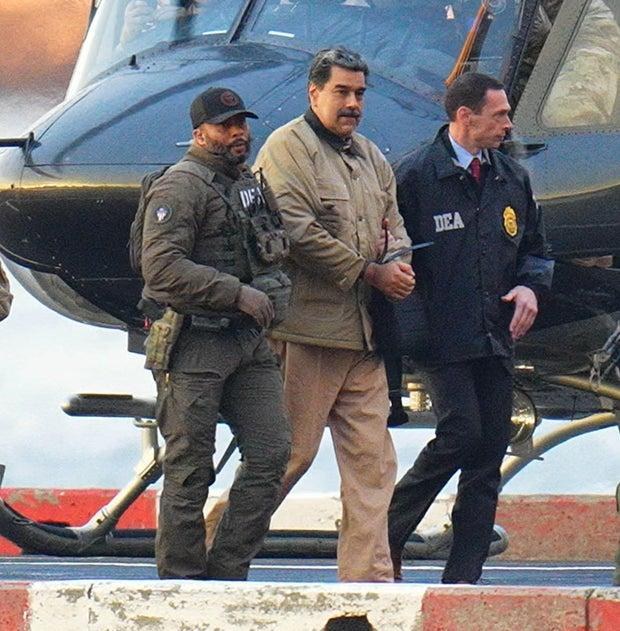 Former Venezuelan President Nicolás Maduro is escorted by U.S. Drug Enforcement Administration personnel following his capture in January 2026. Maduro is scheduled to appear in federal court October 15 on new charges alleging a conspiracy to torture