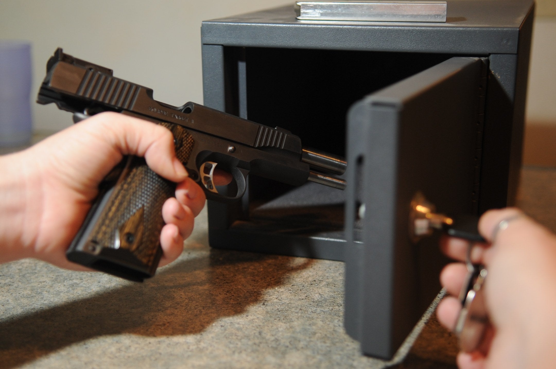 A handgun is placed into a lockable safe at Minot Air Force Base. Five months after Pete Hegseth ordered a presumption of approval for off-duty personal-firearm carry requests, several major installation websites still post broad concealed-carry