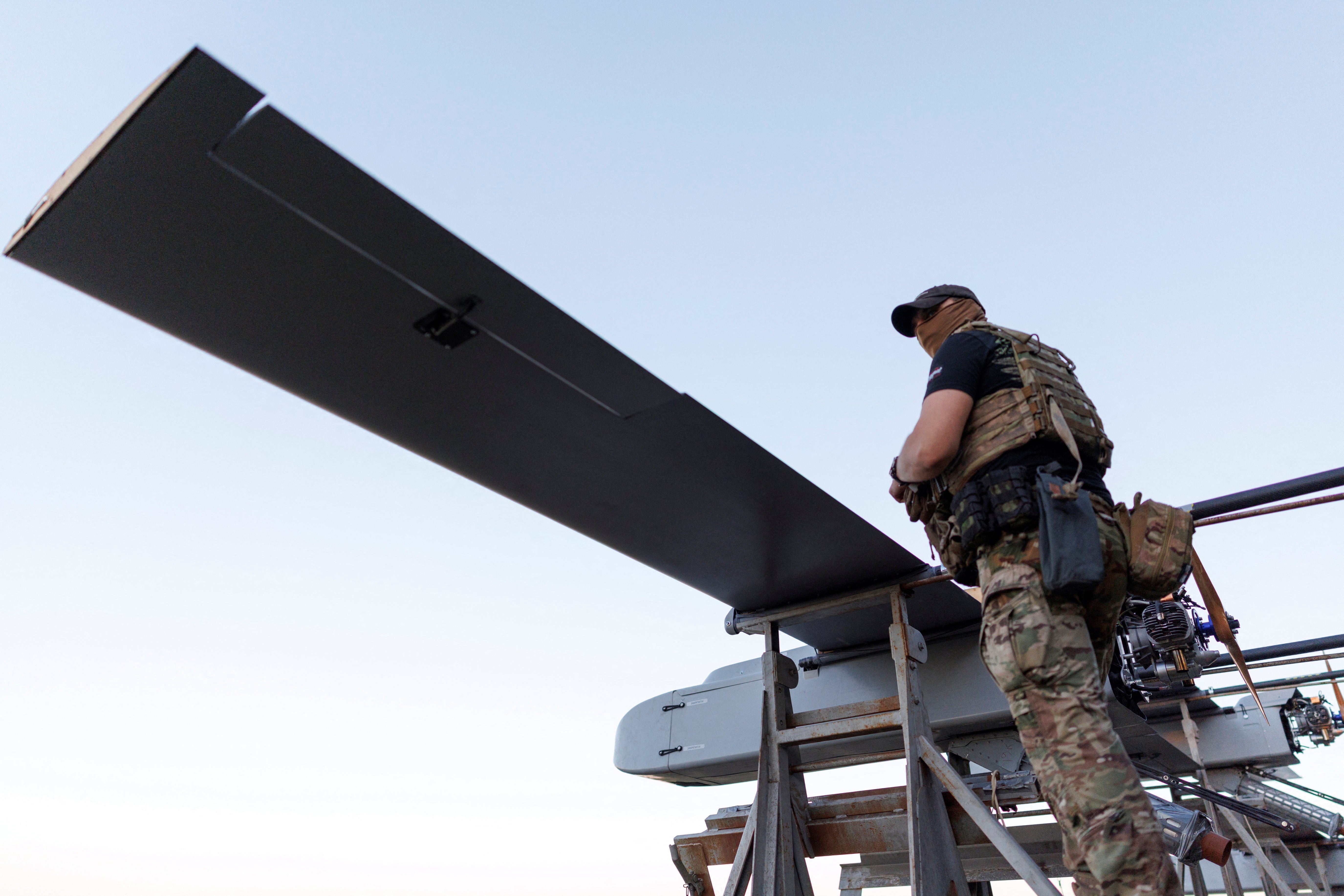 A service member of the 414th Separate Unmanned Strike Aviation System Brigade 'Magyar's Birds' of the Ukrainian Armed Forces stands next to FP-1 deep-strike drones before their launch for a combat mission, amid Russia's attack on Ukraine, in an