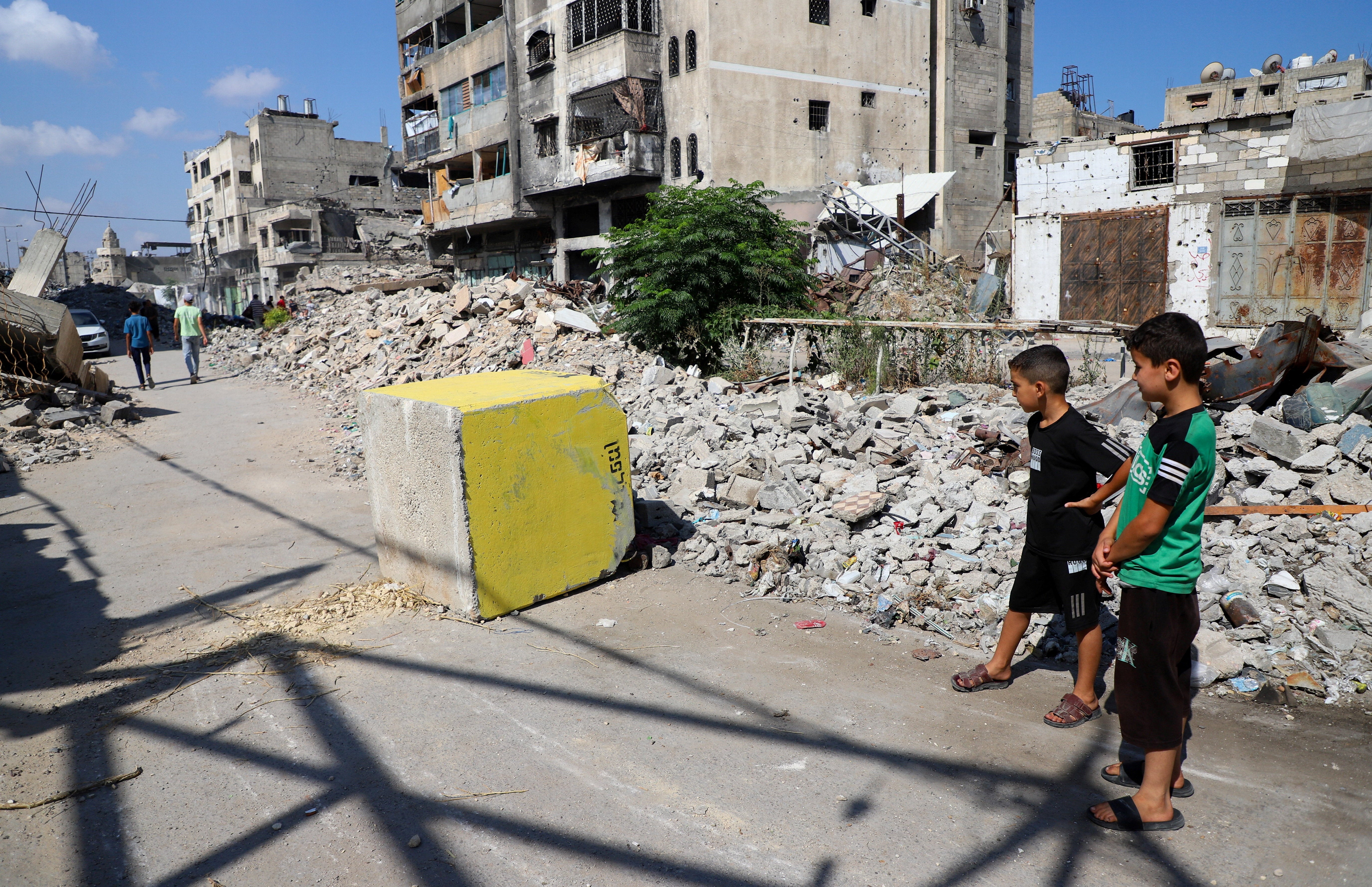 Palestinian boys look at a yellow concrete block marking the "yellow zone" under Israeli military control, in Tufah neighborhood, in Gaza City, July 27, 2026. REUTERS/Ebrahim Hajjaj