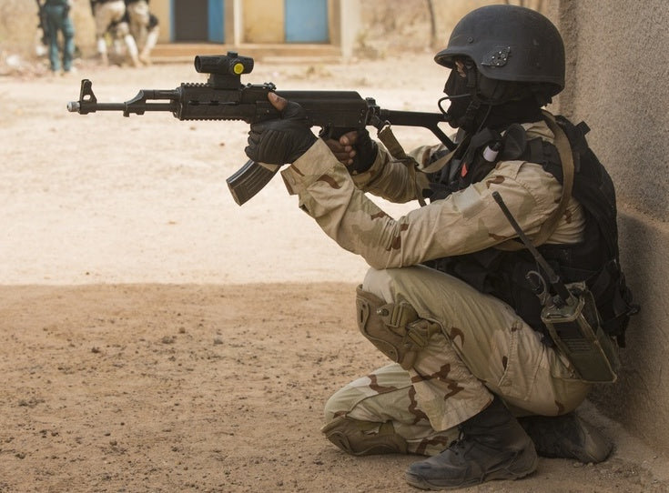 A Burkinabe soldier pulls security while his teammates clear the area of threats at base camp Zagre, Burkina Faso