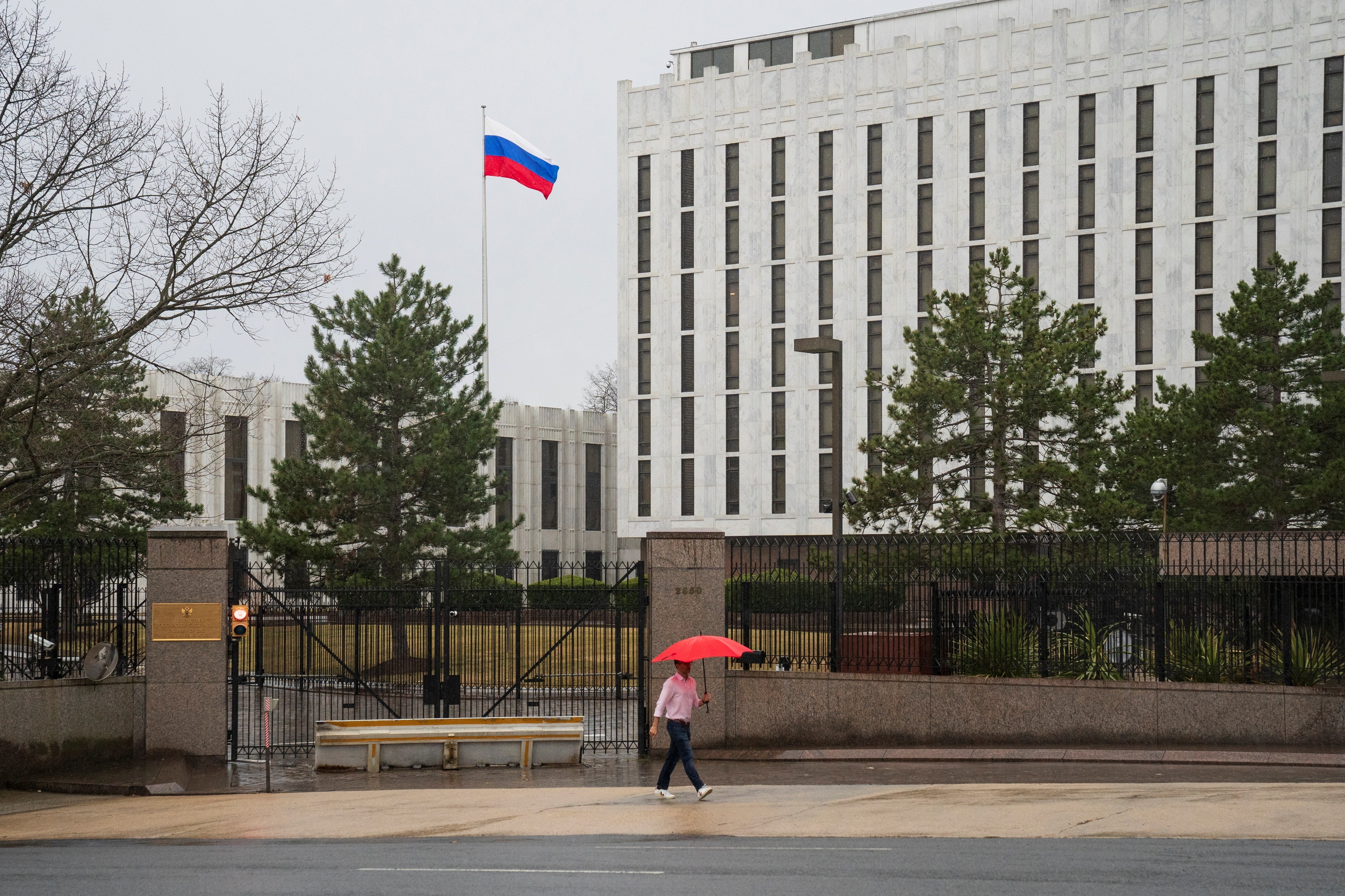 A pedestrian walks with an umbrella outside the Embassy of the Russian Federation, near the Glover Park neighborhood of Washington, U.S