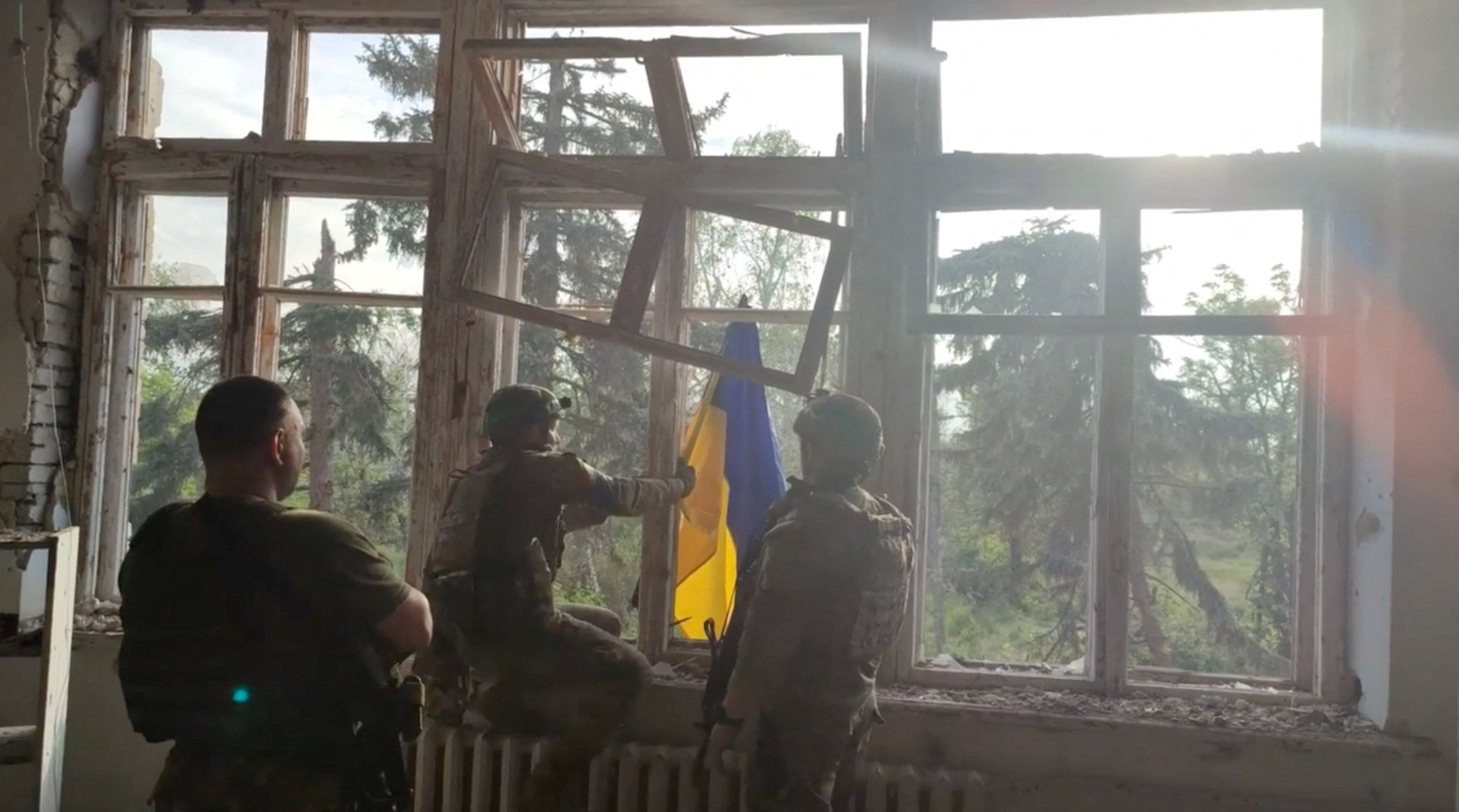  Ukrainian soldiers place a Ukrainian flag at a building, during an operation that claims to liberate the first village amid a counter-offensive