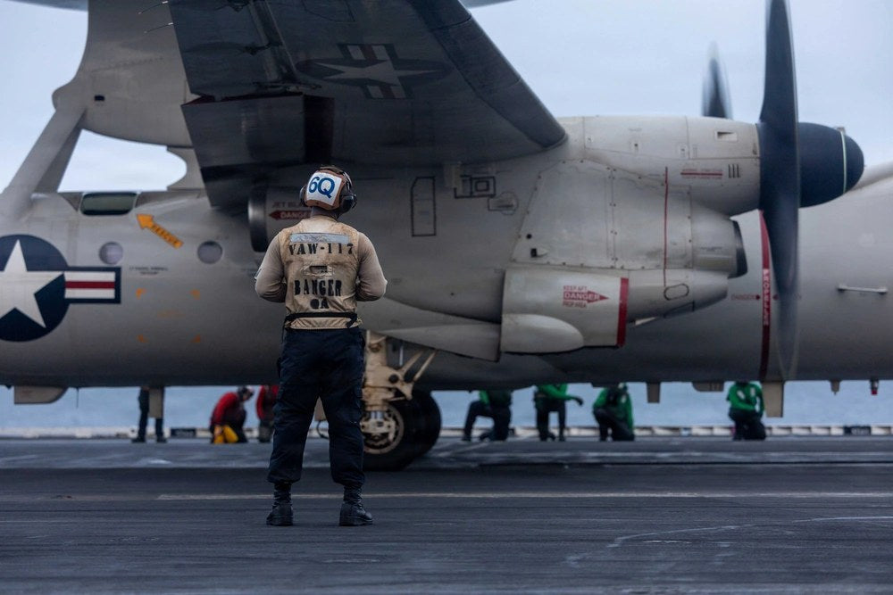 A U.S. sailor assigned to Airborne Command & Control Squadron 117 observes flight operations from the flight deck of the USS Abraham Lincoln on Aug. 11, 2026. U.S. Navy photo via NAVCENT Public Affairs.