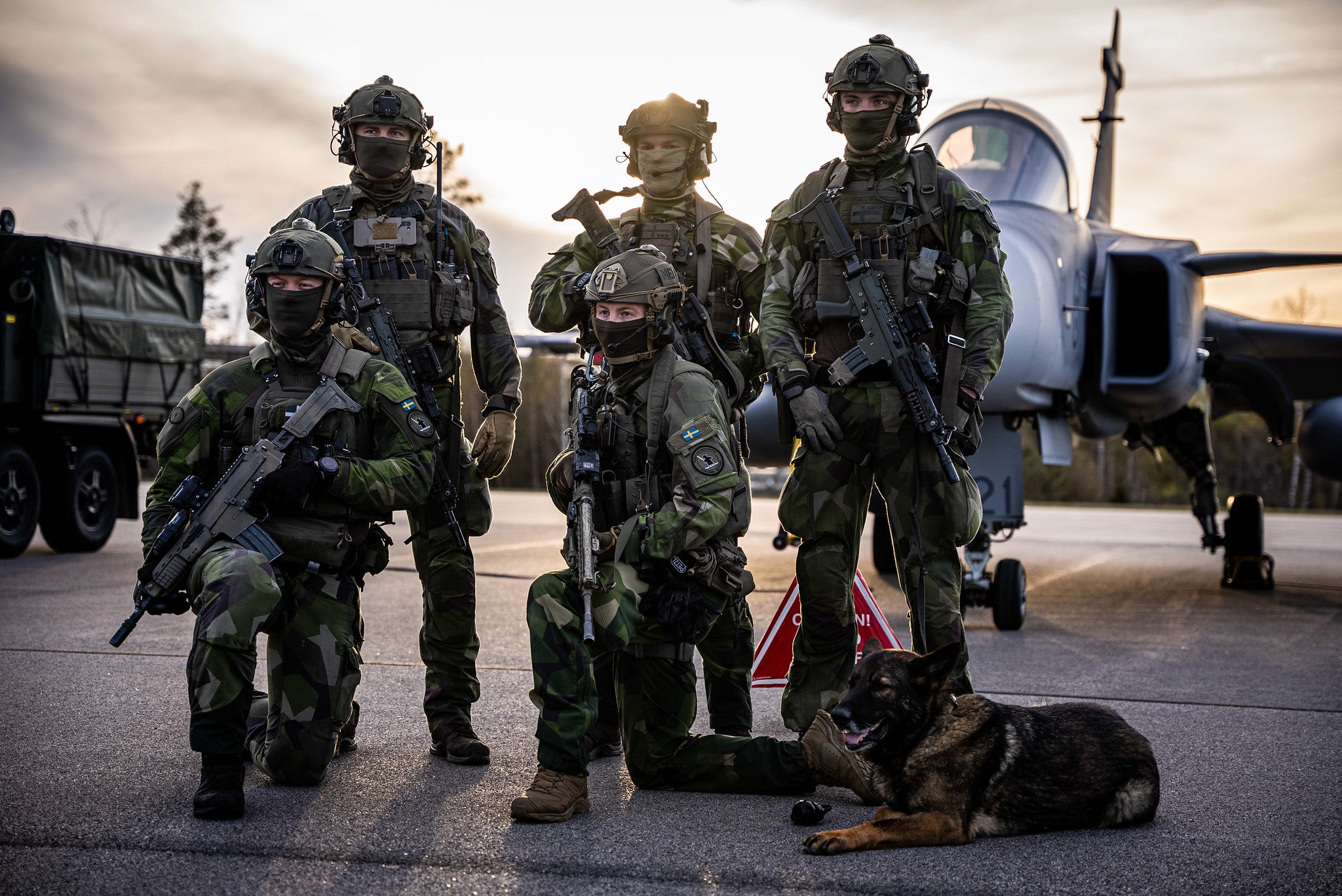 A team of Swedish Air Force Rangers pose in front of a JAS-39 Gripen fighter jet