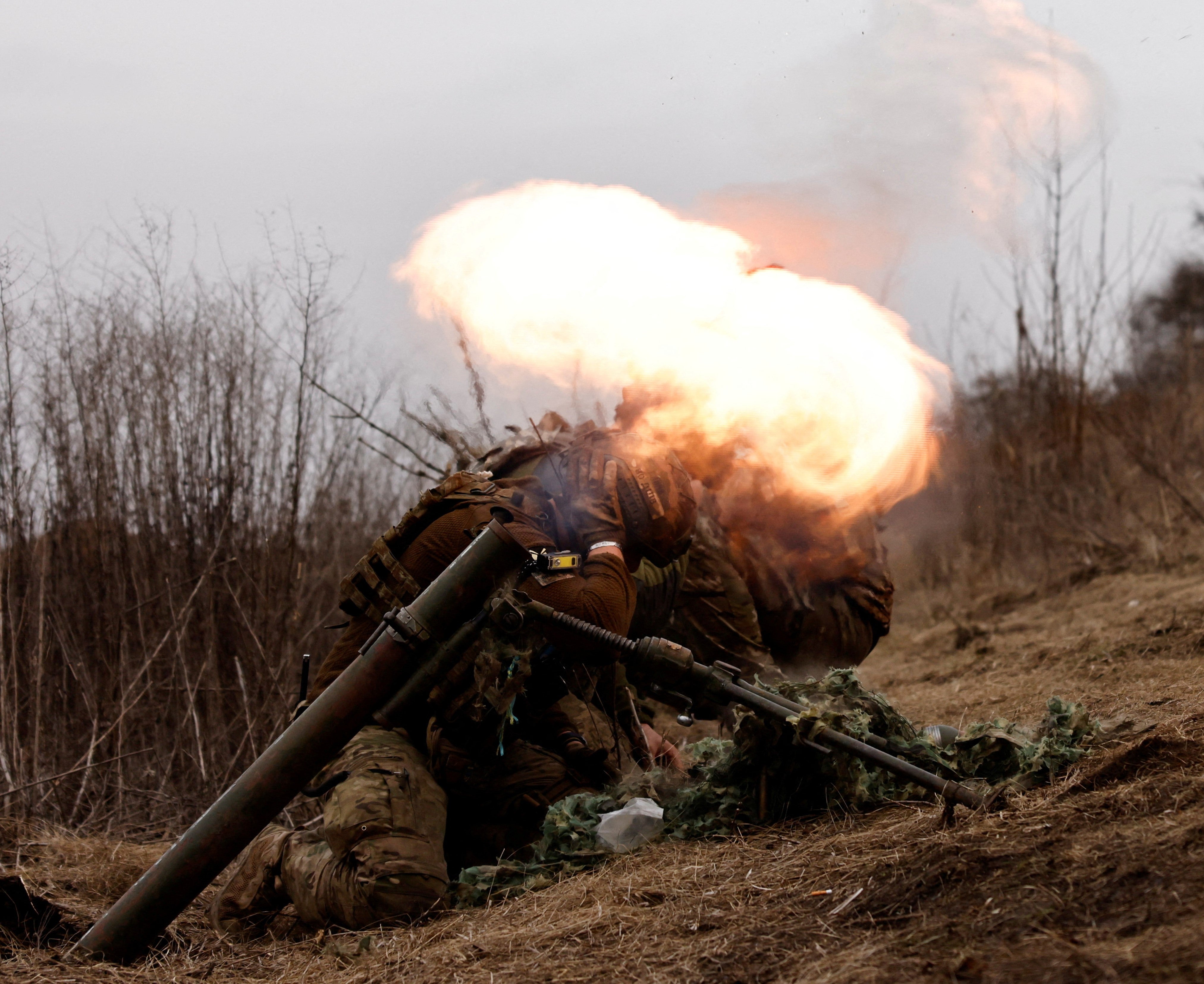 Ukrainian soldiers of the Paratroopers' of 80th brigade take cover as they fire a mortar shell at a frontline position near Bakhmut