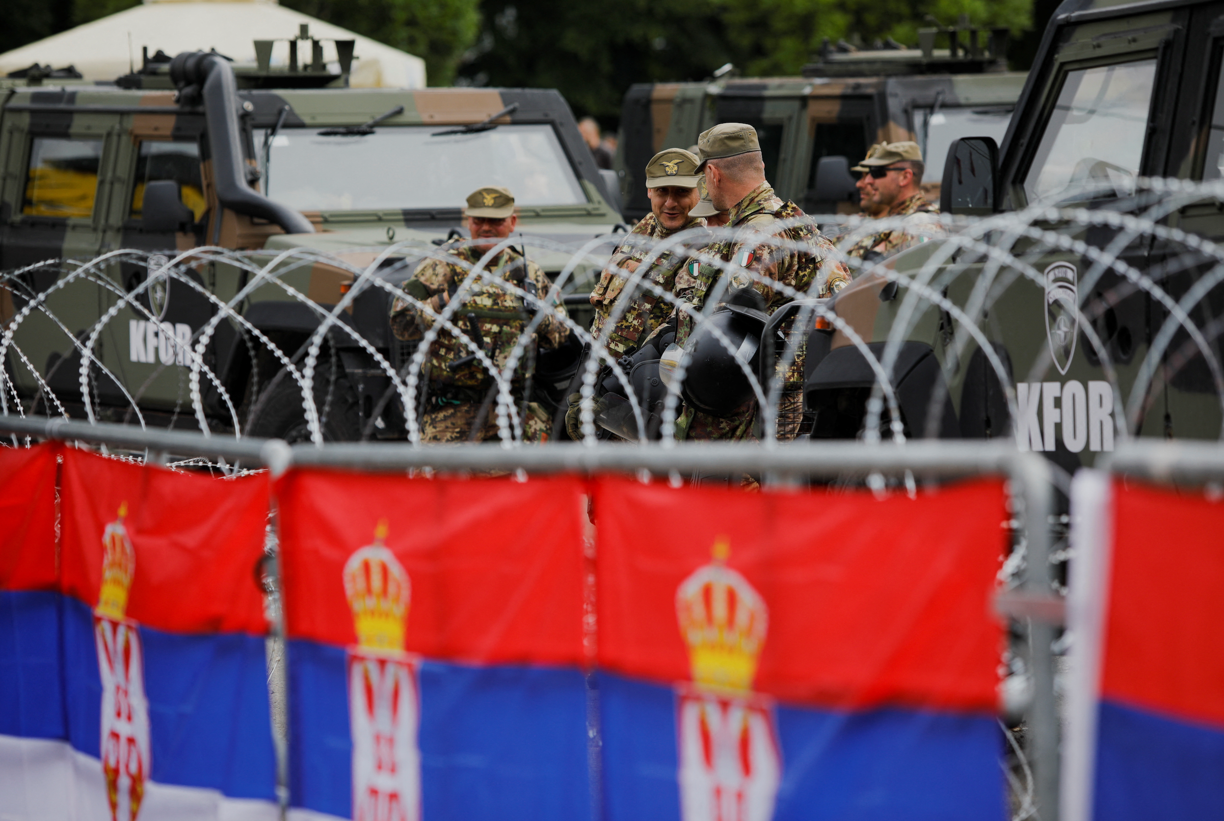 Italian members of the NATO-led Kosovo Force (KFOR) stand guard behind wire fencing, in Leposavic