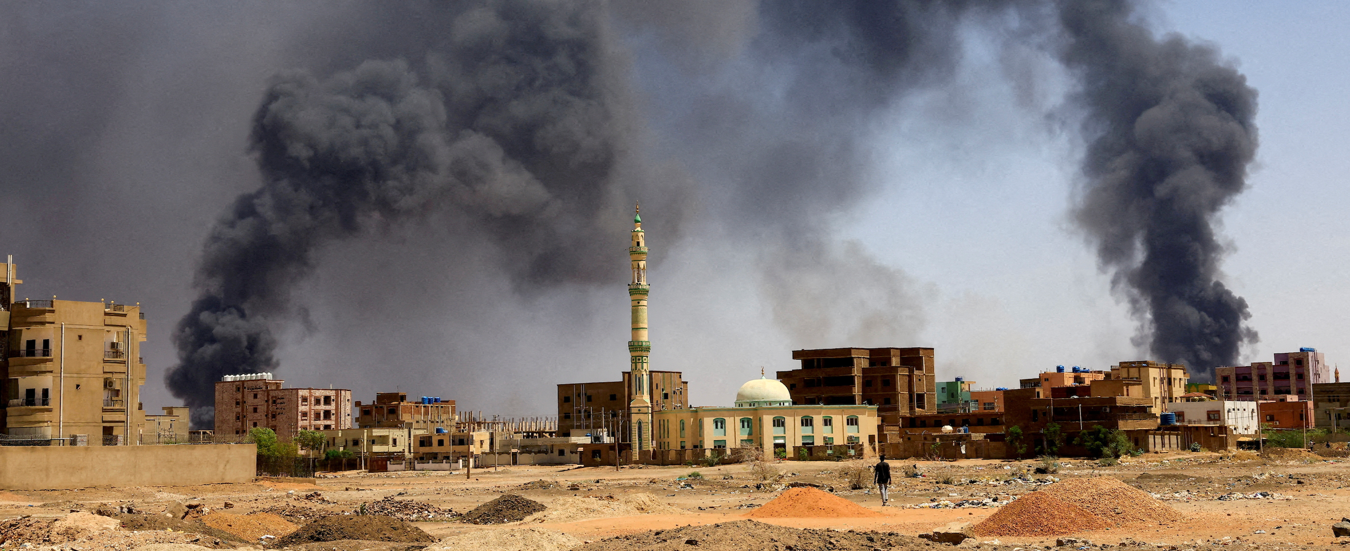 A man walks while smoke rises above buildings after aerial bombardment, during clashes between the paramilitary Rapid Support Forces and the army in Khartoum North, Sudan, May 1, 2023