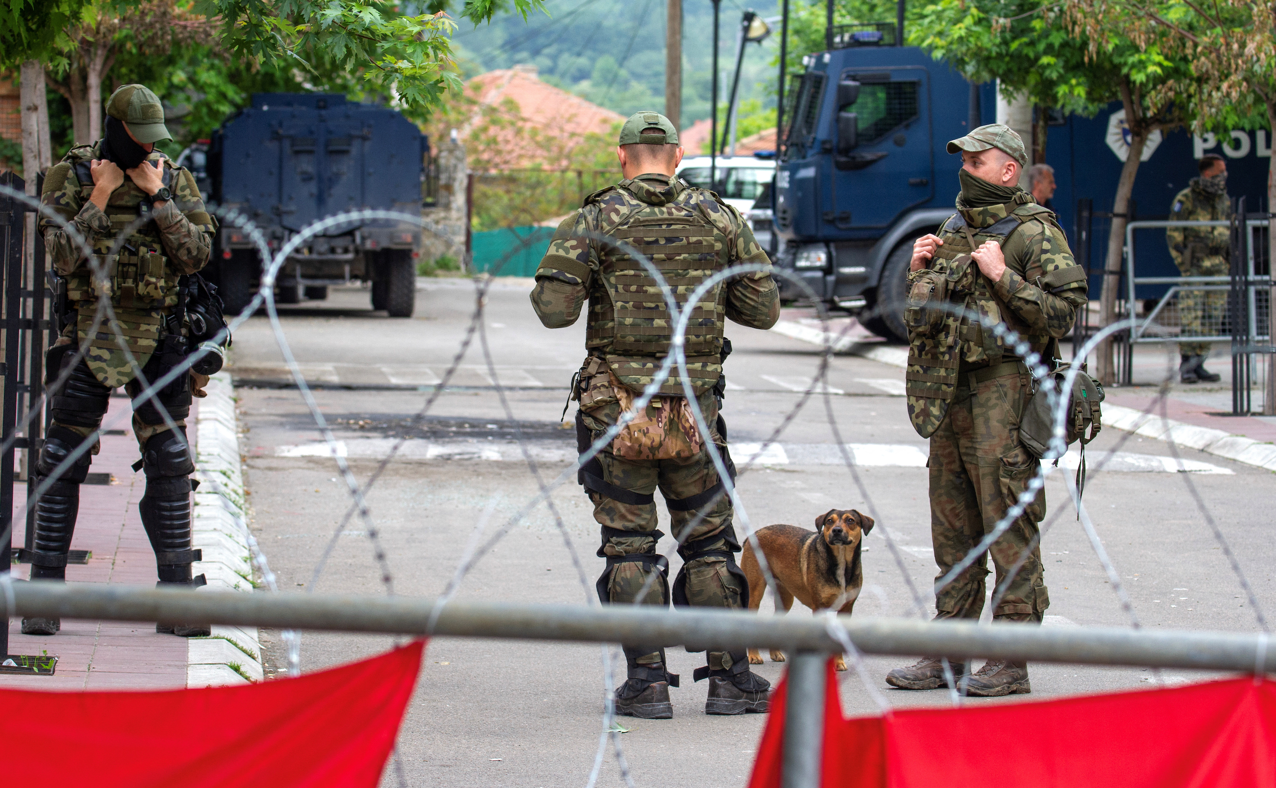 NATO Kosovo Force (KFOR) soldiers stand guard behind razor wire fence in the town of Zvecan, Kosovo