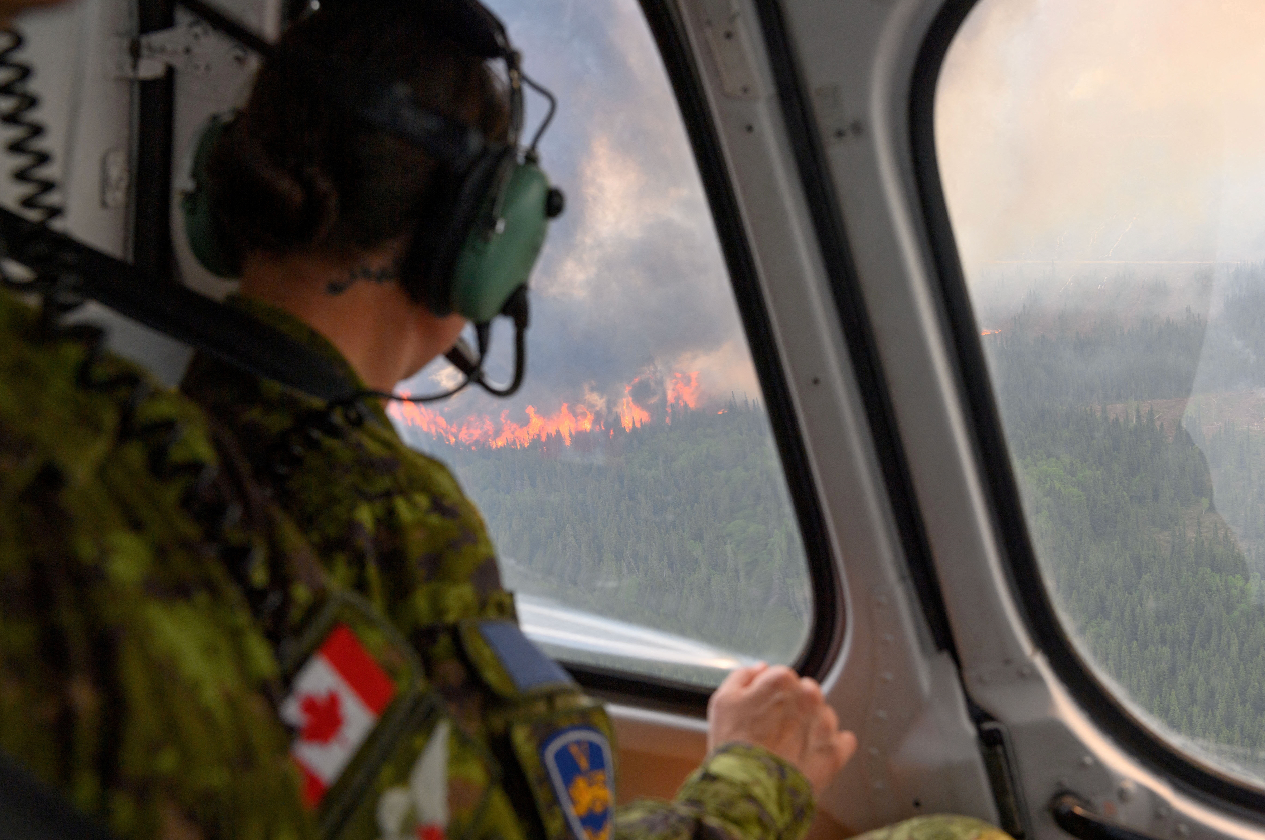 A soldier of the 5th Canadian Mechanized Brigade Group (5 CMBG) views a wildfire from a Canadian Forces helicopter