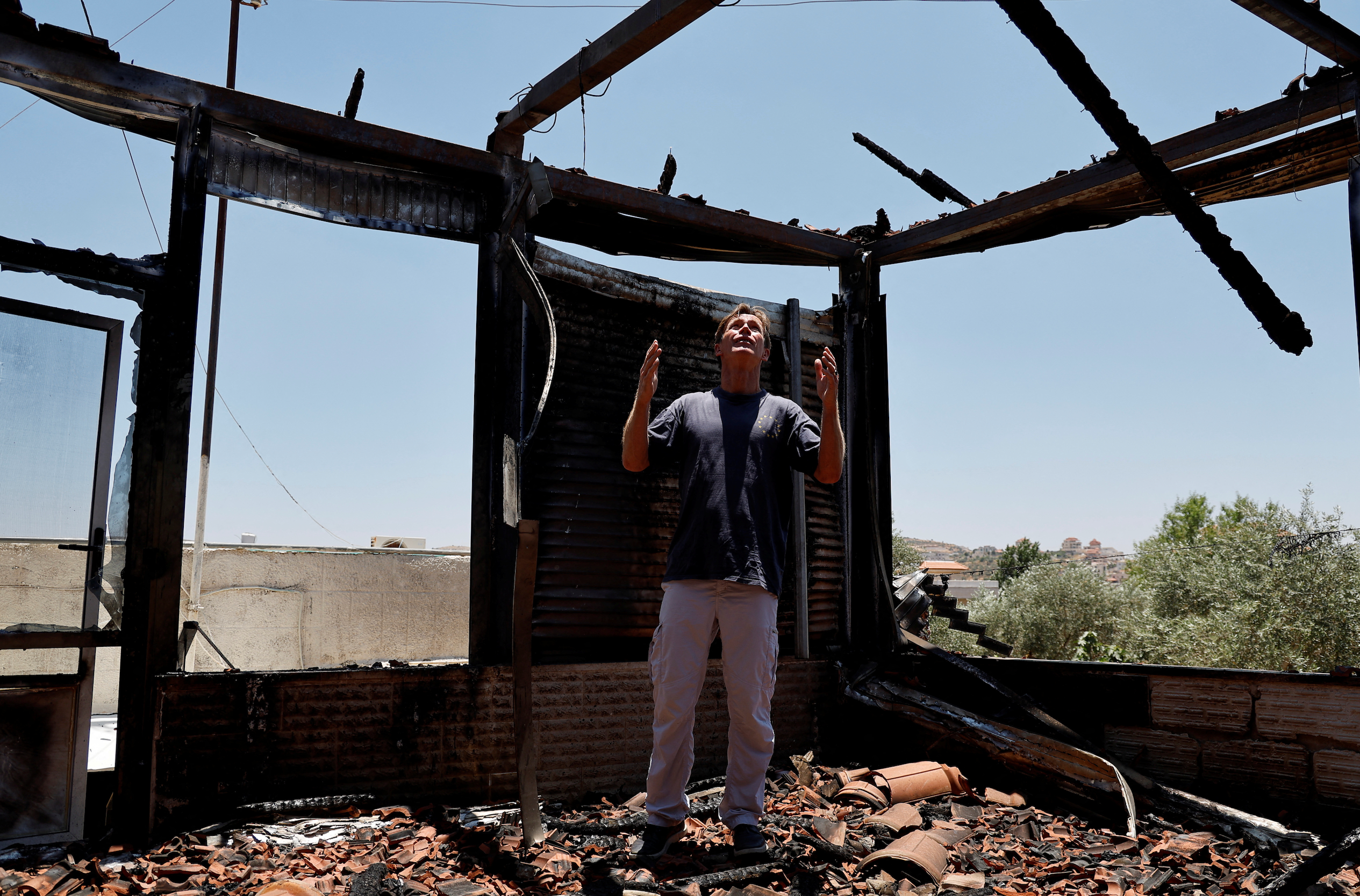 A European diplomat checks a Palestinian house that was torched by Israeli settlers