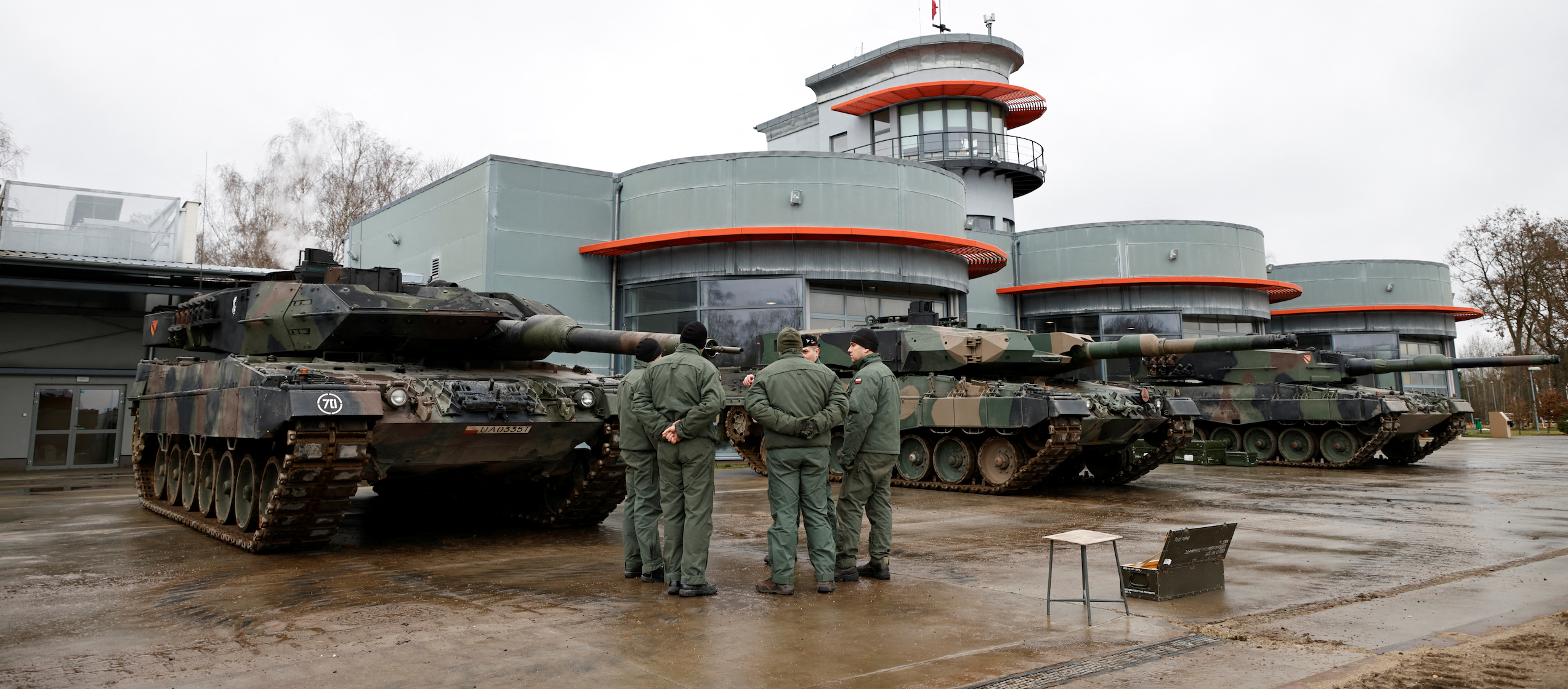 A Polish army instructor stands with Polish soldiers in front of a Leopard 2A5