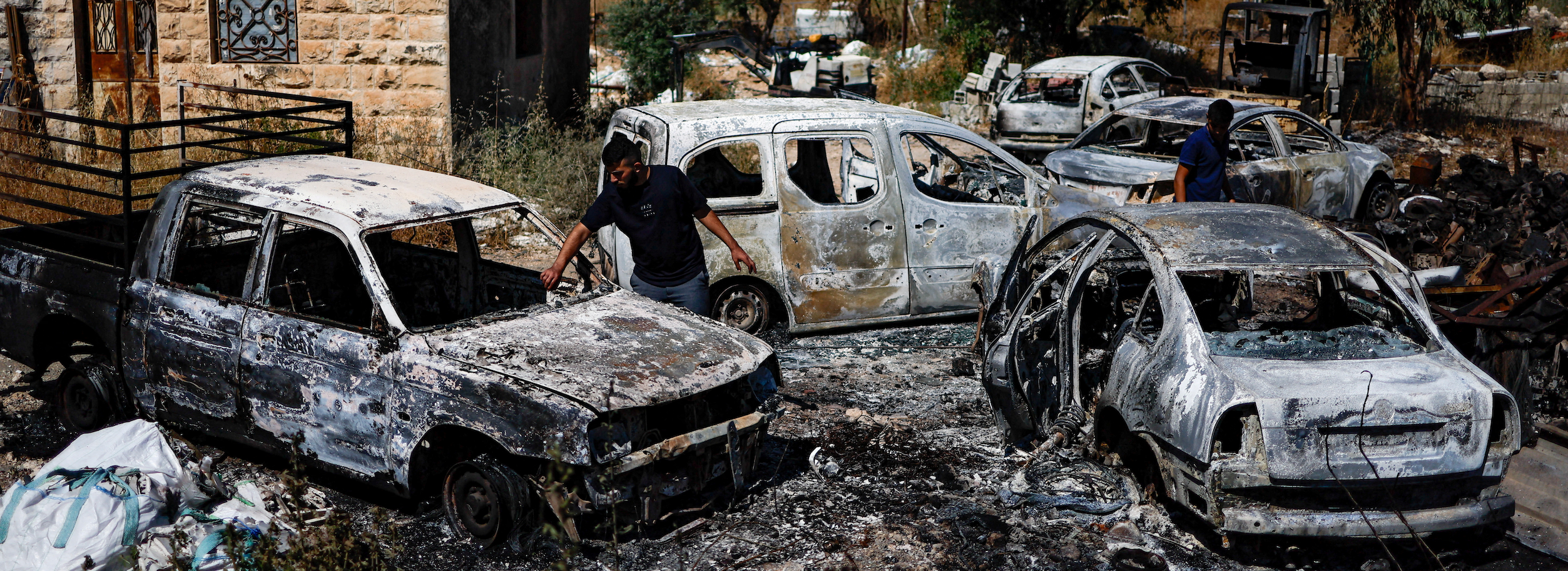 Palestinians check burned vehicles after Israeli settlers attack near Ramallah in the Israeli-occupied West Bank