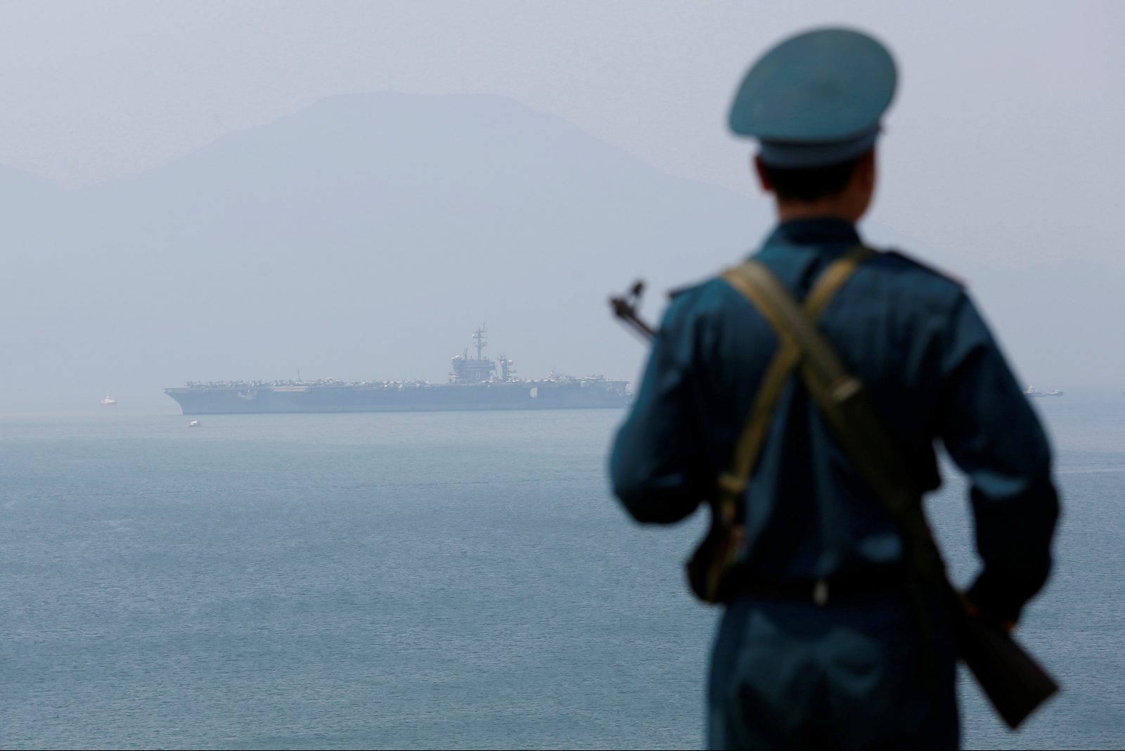 A Vietnamese soldier keeps watch in front of U.S. aircraft carrier USS Carl Vinson
