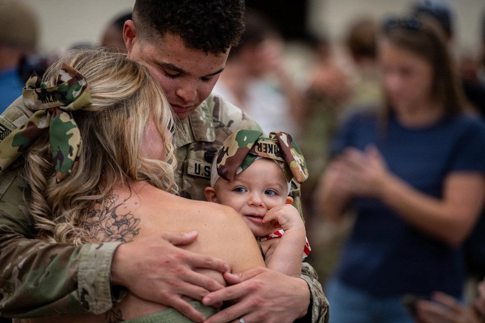 An Oklahoma Army National Guard soldier embraces family after returning from a nine-month deployment to the Middle East on Aug. 20, 2026. The image is illustrative of the strain extended deployments can place on service members and their families.