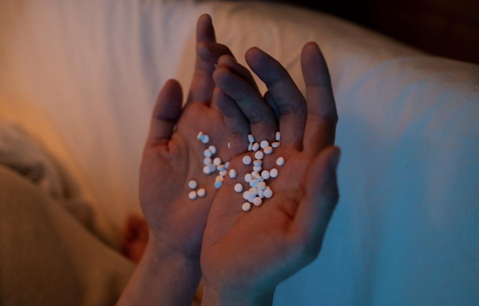 An illustrative photograph shows pills held in a person's hands. Federal prosecutors allege operators of a Southern California addiction treatment network drugged patients to prevent them from leaving while submitting more than $1.6 billion in fraudulent