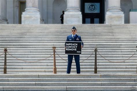 U.S. Air Force Maj. Jason Watson stands on the U.S. Capitol steps in uniform on July 1, 2026, holding a sign calling for the impeachment, conviction and removal of President Donald Trump and Vice President JD Vance.
