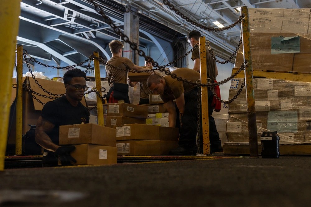 U.S. sailors move supplies aboard the USS Abraham Lincoln during a replenishment-at-sea in the U.S. 5th Fleet area in May 2026. The carrier’s extended deployment later drew scrutiny over logistics, supplies and crew living conditions. U.S. Navy photo.