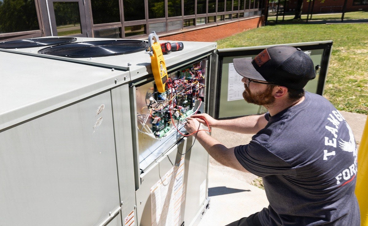 A contractor works on a heating and air conditioning unit at Fort Knox’s Disney Barracks in May 2026. The Army has established a nationwide HVAC task force to address heating and cooling problems across military installations. (U.S. Army photo)
