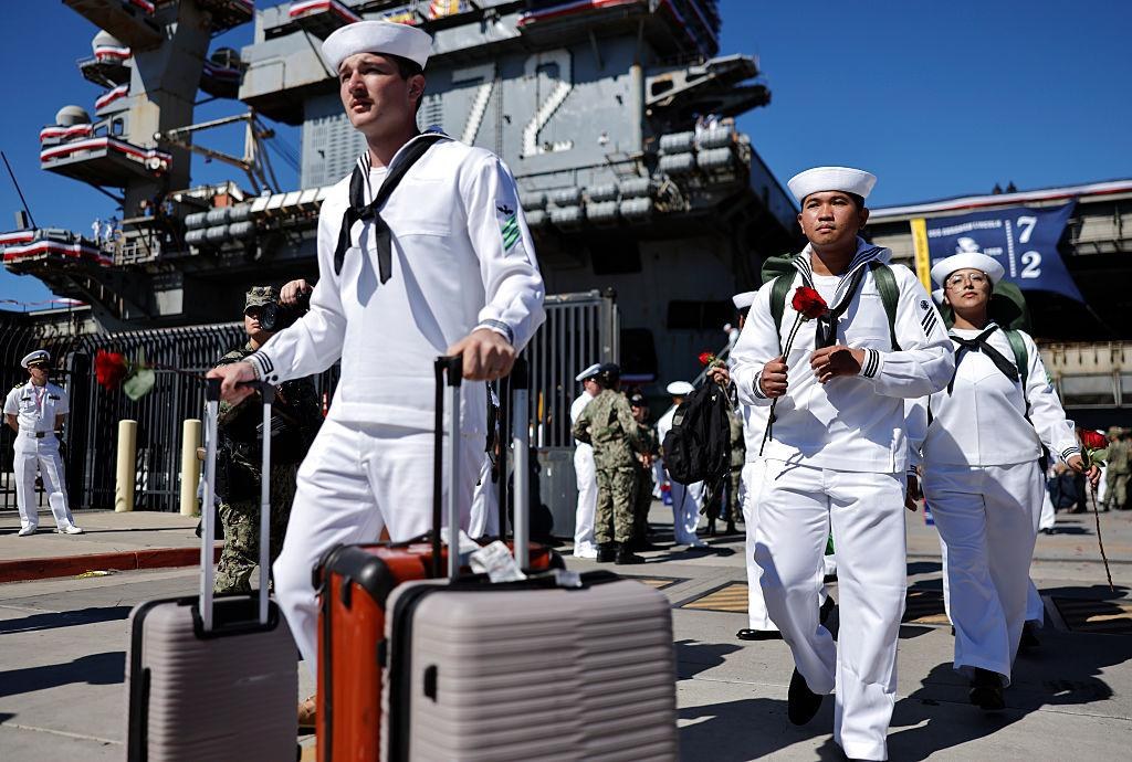 Sailors depart the USS Abraham Lincoln after the aircraft carrier returned to San Diego on October 8, 2026, following a 321-day deployment. The Navy has since confirmed the carrier will change home ports to Bremerton, Washington, by the end of the year,