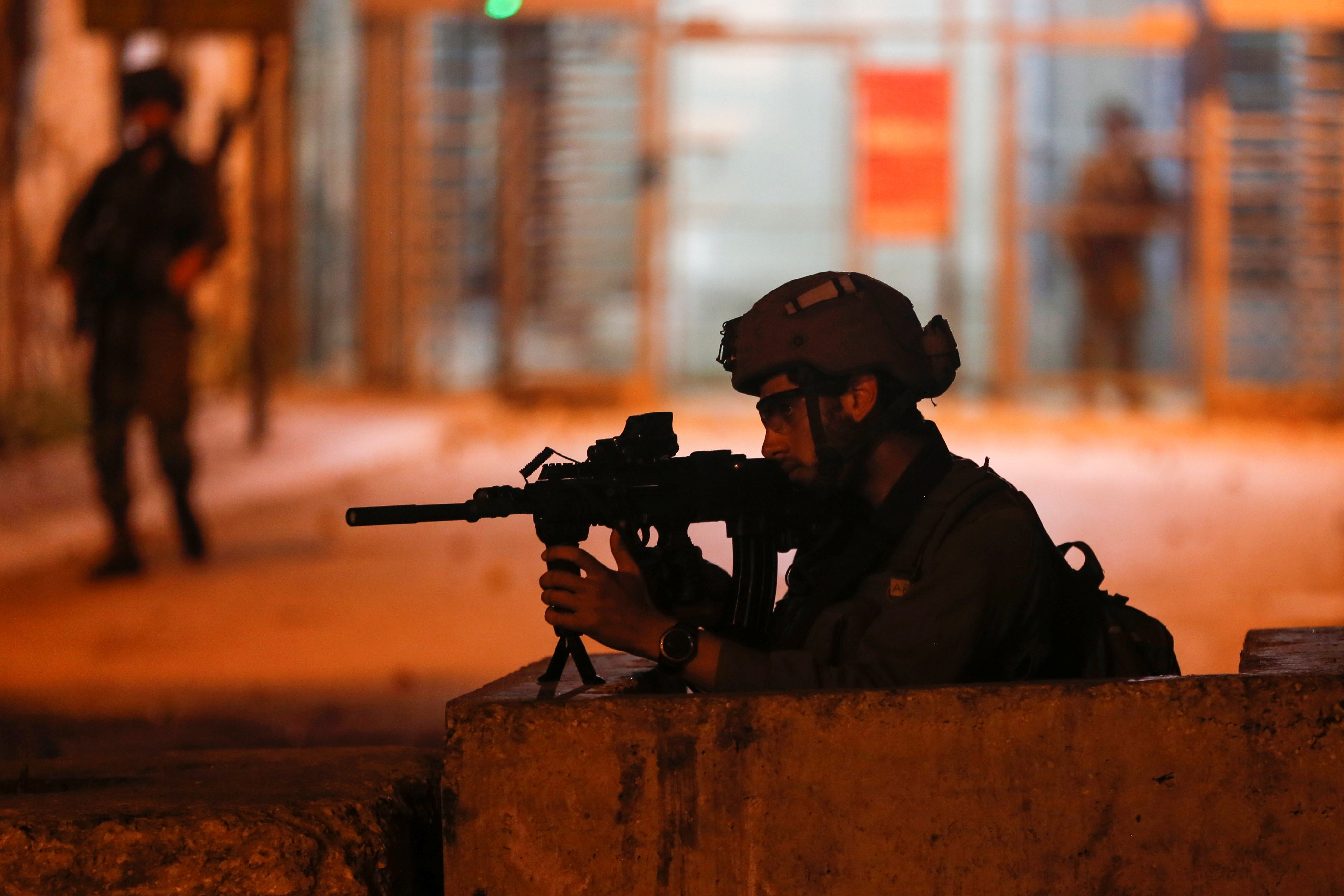  member of Israeli forces aims his weapon as Palestinians take part in an anti-Israel protest over tension in Jerusalem, in Hebron in the Israeli-occupied West Bank