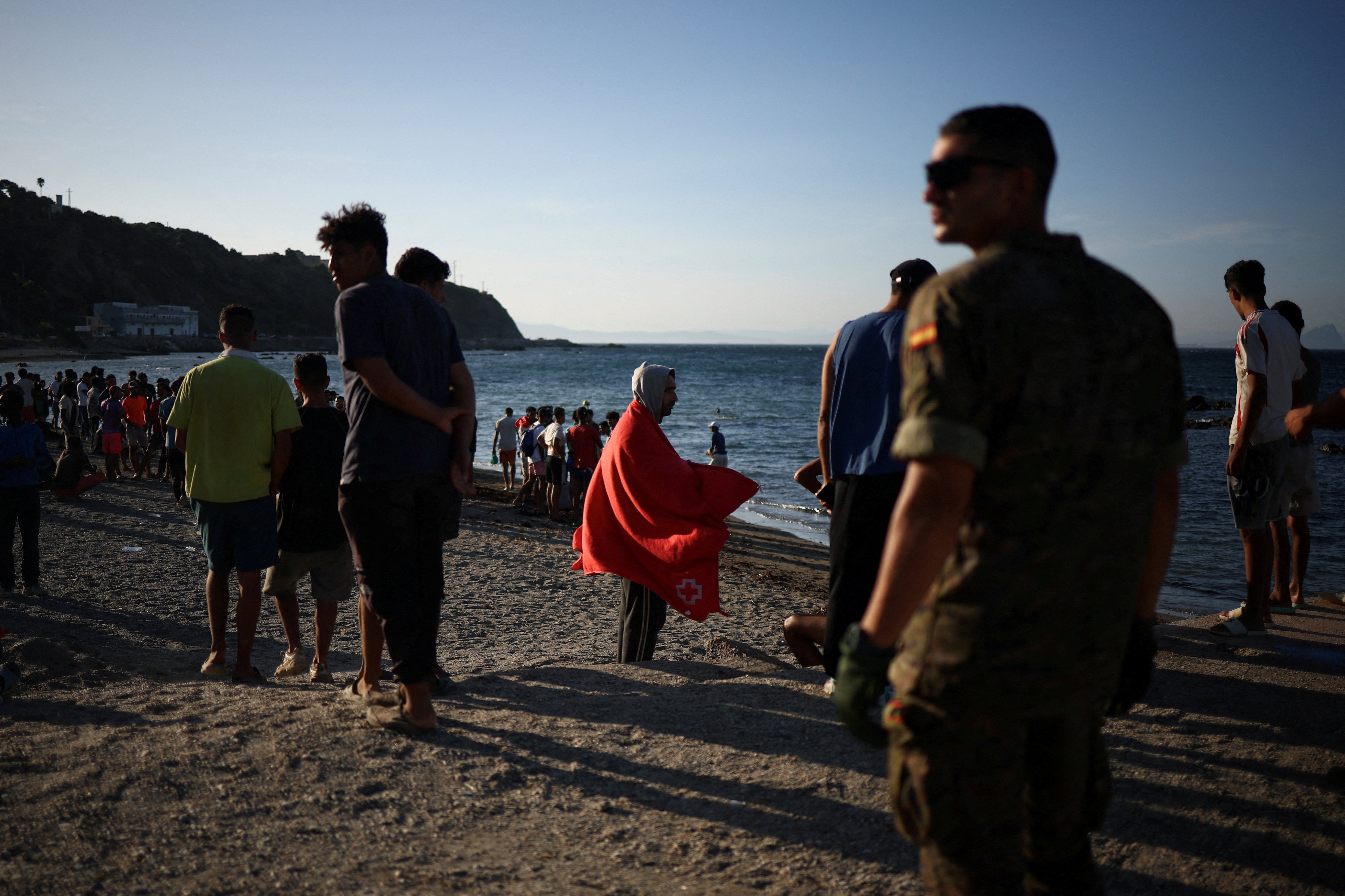 Migrants stand on a beach in Ceuta, following mass crossings of migrants on foot and by sea from Morocco into Spanish territory, in Ceuta, Spain, August 2, 2026. REUTERS/Pedro Nunes