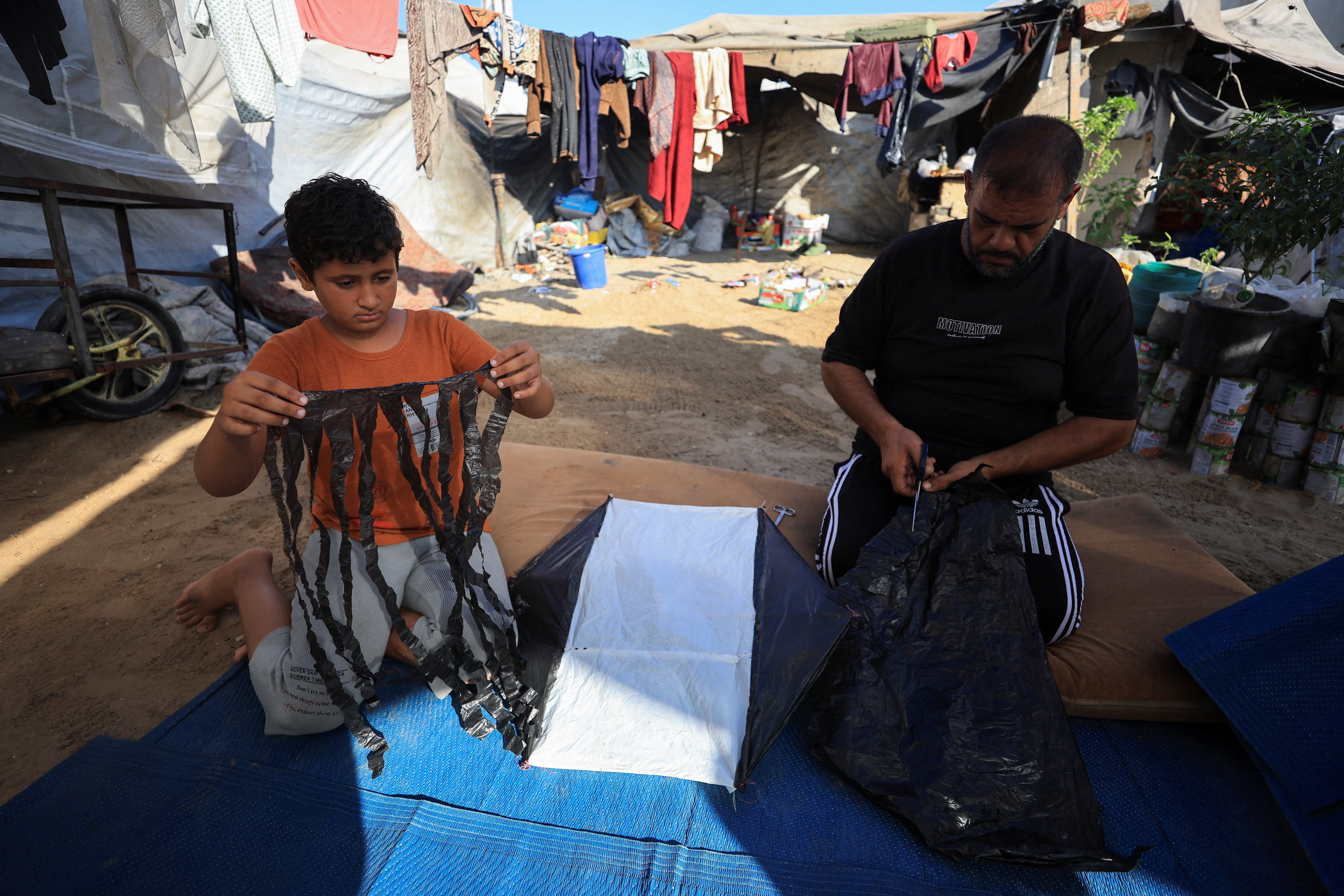 Palestinians make a kite at a tent camp sheltering displaced people in Gaza City, August 25, 2026. REUTERS/Dawoud Abu Alkas
